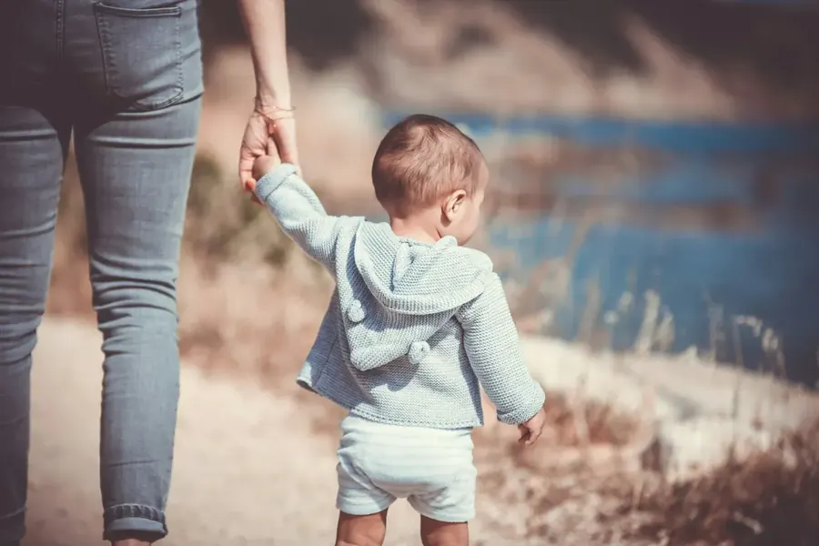 Toddler walking holding a parent's hand