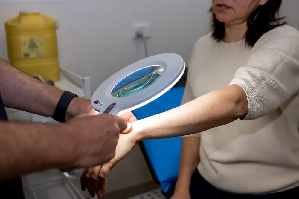Doctor examining a patient's arm with a dermatoscope